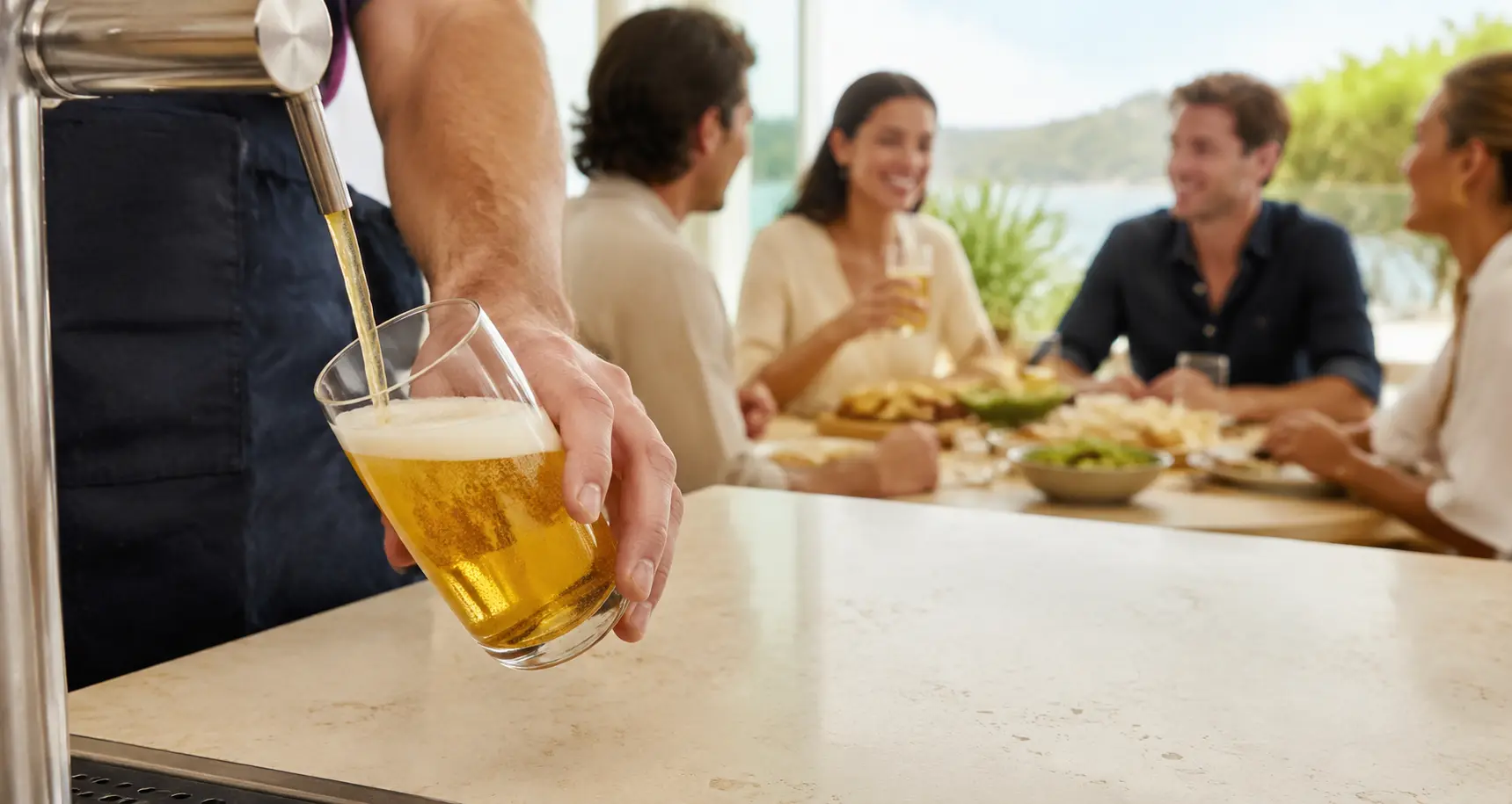 Golden lager poured with care while adult friends share food nearby